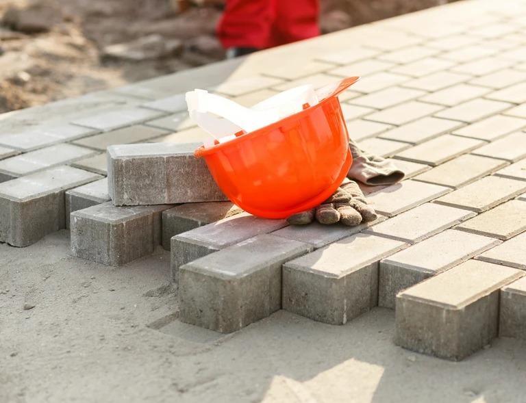 Układanie kostki brukowej i pomarańczowy kask